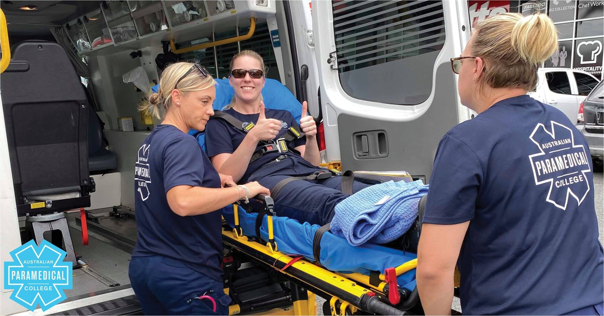 Nurse to Paramedic advice. Female paramedical students load patient into ambulance
